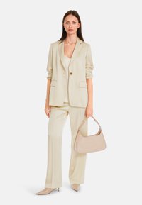Cream blazer with matching wide-leg trousers, a beige handbag, and pointed heels create a polished, monochromatic look.