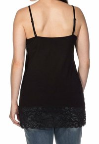Camiseta sin mangas negra con tirantes ajustables finos. Presenta un borde de encaje en el dobladillo. Tela suave con un corte relajado, mostrada desde la parte posterior.