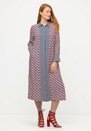 Robe longue à motifs floraux avec un panneau avant rayé, dotée de manches longues et de poches latérales, assortie de sandales à talons rouges.