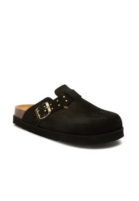 Zwarte suède instapklompen met kurken zool, zwarte rubberen buitenzool en een gouden gespsband met kleine gouden studs.