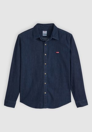 Dark denim button-up shirt with a pointed collar, long sleeves, and a small red logo on the chest. Features brass buttons and a classic fit.