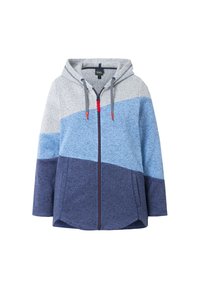 Bunda s kapucí a zipem vpředu, vyrobená z silné tkaniny. Má design v barvách bloků s šedými, světle modrými a tmavě modrými sekcemi. Ozdobena červeným táhlem zipu.