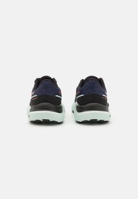 Chaussures de sport avec une tige en mesh noir et marine, une semelle intermédiaire vert menthe et une semelle extérieure texturée. Affiche un logo avec des accents orange.