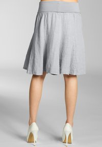 Grauer Leinen-A-Linie-Rock mit flachem, elastischem Bund, der bis zur Mitte der Wade reicht. Der Stoff hat eine leicht strukturierte Oberfläche und fließt locker.