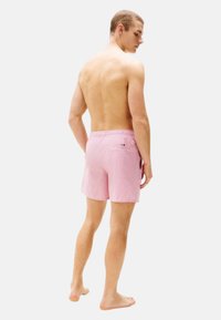 Shorts de bain roses avec un motif texturé, taille élastique et poche arrière, conçus pour le confort et un style décontracté.