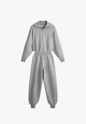 Grå zip-up jumpsuit med hög krage, vida ärmar, elastisk midja och avsmalnande ben, tillverkad av ett mjukt och mysigt material.