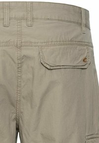 Khaki shorts van lichtgewicht stof met een gladde textuur, voorzien van twee achterzakken en een logo-accent aan de rechterzijde.