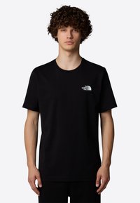 Sort bomulds T-shirt med korte ærmer, rund hals og et lille hvidt logo på venstre bryst. Glat tekstur og afslappet pasform.