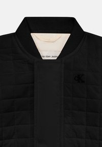 Μαύρο καπιτονέ κολάρο μπουφάν με ριμπ λαιμόκοψη, κρυφή εμπρόσθια κλείστρα και διακριτικό κεντητό λογότυπο CK στο στήθος.