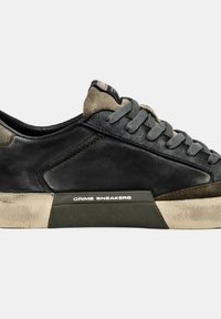 Sneaker in pelle nera con accenti grigi, superficie strutturata, lacci piatti e suola in gomma con un logo bianco di lato.