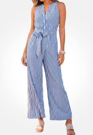Bezrękawnikowy kombinezon w pionowe niebiesko-białe paski z guzikami i paskiem w talii, noszony z białymi klapkami i bransoletkami.