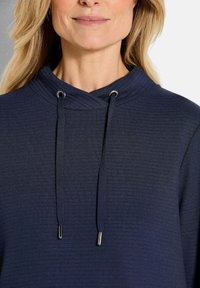 Felpa navy con un motivo testurizzato, scollatura incrociata e lacci in metallo argentato con punte.
