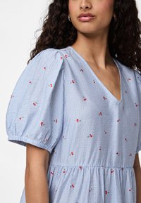 Μπλε και λευκό ριγέ φόρεμα με φουσκωτά μανίκια, V-λαιμόκοψη και κόκκινη λουλουδάτη κεντητική διακόσμηση. Μαλακό ύφασμα με μαζεμένη μέση και πτυχώσεις.