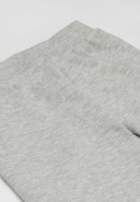 Miękkie szare legginsy z materiału złożone, ukazujące elastyczny pas i prążkowaną teksturę, na białym tle.