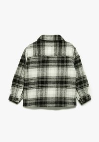 Mustasta ja valkoisesta ruudullisesta flanellipaidasta, jossa on kauluspääntie, pitkät hihat ja nappihaarat. Teksturoitu, pehmeä kangas.