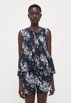 Kwiecowy top peplum w granatowo-białym kolorze z guziczkowym dekoltem w kształcie łezki; charakteryzuje się luźnym krojem i bezrękawowym fasonem, w połączeniu z pasującymi szortami.