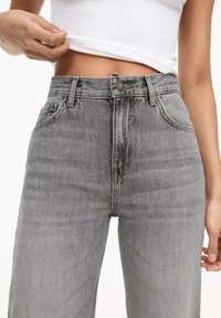 Jean en denim gris taille haute avec une texture lisse, doté de poches avant, de passants pour ceinture et d'une fermeture à bouton métallique.