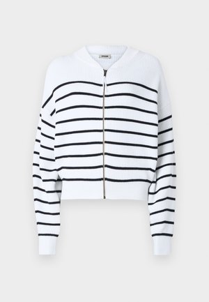 Hvit avkortet genser med svarte horisontale striper, ribbet tekstur, glidelås foran og rund hals. Har senkede skuldre og tettsittende mansjetter.