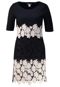 Robe noire à manches courtes, avec une superposition en dentelle de motifs floraux crème le long de la moitié inférieure et un col rond.