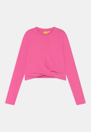 Top de manga larga y corte corto en tela de color rosa brillante con un detalle anudado en la parte frontal. Textura lisa, escote redondo y sin herrajes visibles.