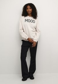 Helle, strukturierte Sweatshirt mit dem Aufdruck "MOOD" in dunklen Streifen, kombiniert mit schwarzen, ausgestellten Hosen. Einfaches, lässiges Design.