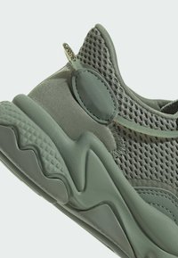 Jasnozielone trampki z siateczkową cholewką, gładkimi skórzanymi akcentami, teksturowaną podeszwą i pętelką ułatwiającą zakładanie.