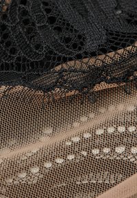 Zwarte kanten overlay op beige gaas, met ingewikkelde patronen en open weefstructuren. Glad textuur met kleine, semi-doorzichtige details verspreid over het geheel.