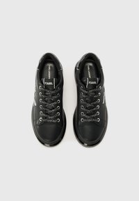 Baskets en cuir noir avec des lacets texturés noirs et des accents argentés. Dotées d'une forme arrondie à l'avant et d'une semelle noire brillante. Logo de la marque visible sur la languette.