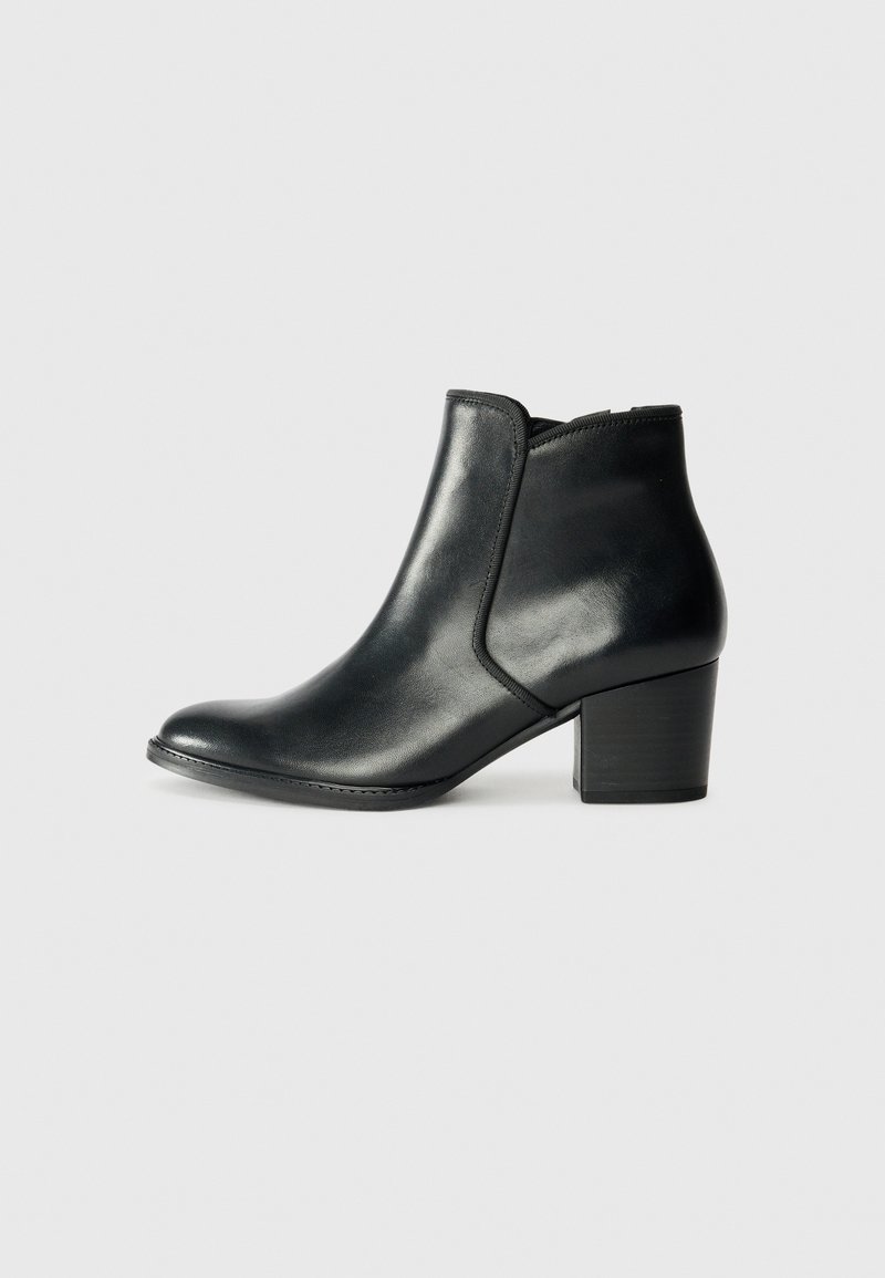 Botas de tobillo negras de cuero con punta redondeada, paneles laterales elásticos y un bajo tacón cuadrado. Textura lisa con un diseño elegante y minimalista.