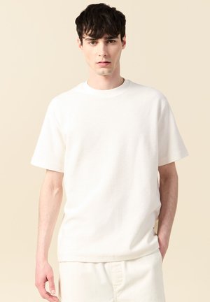 T-shirt bianco a maniche corte realizzato in tessuto testurizzato, con scollo rotondo e una vestibilità comoda. Design semplice senza motivi visibili.