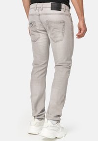 Jeans in denim grigio chiaro con una vestibilità slim, caratterizzati da una finitura testurizzata e dettagli cuciti. Due tasche posteriori e un'etichetta del marchio nera in vita.