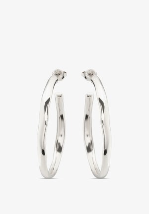 Paire de boucles d'oreilles en argent brillant en forme de créoles aux contours légèrement irréguliers et ondulés, avec des attaches à tige sécurisées, sur fond blanc.