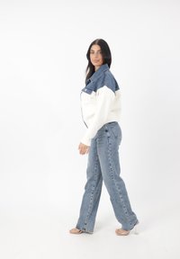 Blå denimjacka med vita ärmar; har tryckknappar och två framfickor. Matchas med ljusblå jeans och sandaler med genomskinlig klack.