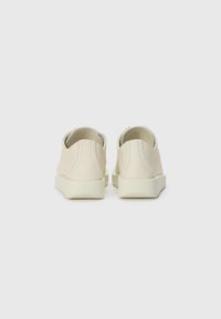 Beige lædersko med lav silhuet, runde bagdele og en glat tekstur. Blød, minimalistisk design med en lys sål.
