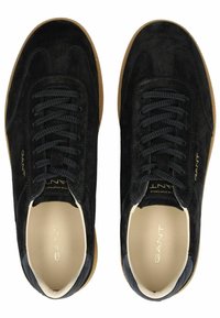 Schwarze Wildledersneaker mit Gummisohle, ausgestattet mit einer runden Zehenpartie, Schnürdesign und dezentem goldenen Branding an der Seite.