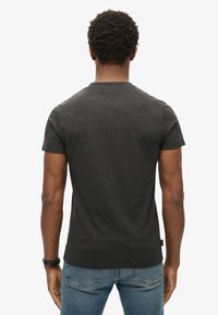 T-shirt a maniche corte grigio scuro con colletto girocollo. Realizzato in tessuto morbido, presenta una vestibilità dritta e dettagli di cucitura minimal.