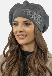 Beret gri tricotat, cu o suprafață texturată și un design decorativ cu strassuri, având un model asimetric de frunze pe o parte.