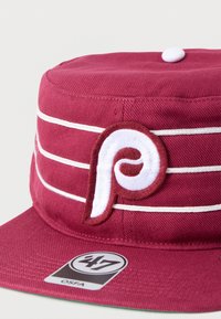 Μπορντό καπέλο μπέιζμπολ με λευκές ρίγες, ένα λευκό κουμπί στην κορυφή και κεντημένο λευκό και μπορντό λογότυπο "P" στο εμπρόσθιο πάνελ.