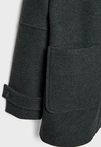 Tmavošedý vlnený kabát s textúrovaným povrchom, s veľkým náprsným vreckom a gombíkovým detailom na manžetách. Prispôsobený dizajn s čistými líniami.