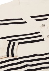 Witte cardigan met zwarte horizontale strepen, voorzien van een v-hals, geribde manchetten en versierde knopen voor extra detail.