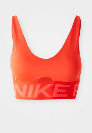 Oransje sports-bh laget av glatt, elastisk materiale med scoop-hals og bred elastisk kant som har gjentatte "NIKE"-logoer i lys rød.