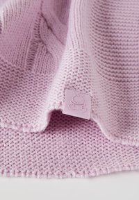 Coperta lavorata a maglia di colore viola chiaro con un motivo testurizzato, caratterizzata da un bordo liscio e un piccolo etichetta in rilievo con un design di coniglio.