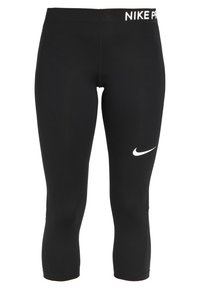 Czarne legginsy Nike Pro typu capri z białym logo na lewej nodze oraz elastycznym pasem, na którym znajduje się napis "NIKE PRO" w białym kolorze. Gładki, elastyczny materiał.