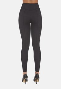 Czarne legginsy z wysokim stanem, wykonane z elastycznego materiału, z kontrastowymi przeszyciami po bokach i gładką teksturą.