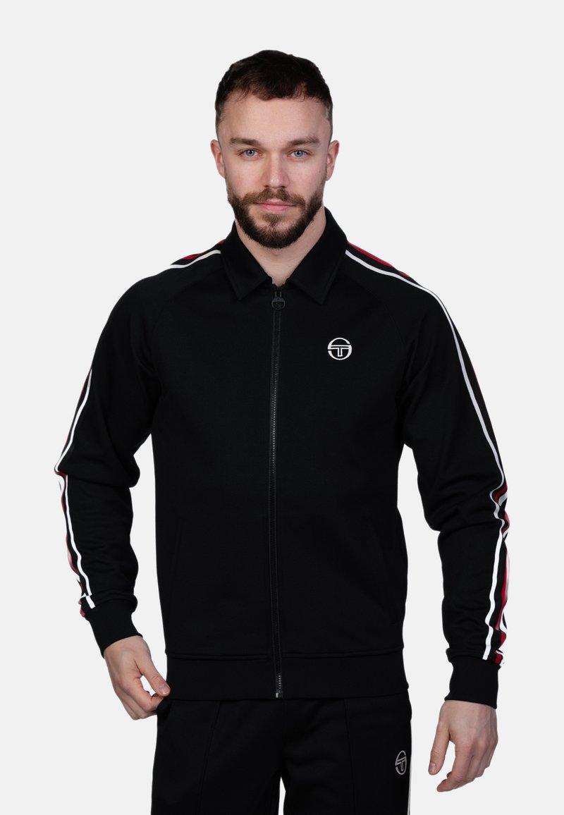 Čierna bunda na zips vyrobená z hladkej látky. Má červené a biele prúžky na rukávoch, rebrované manžety a logo na hrudi.