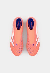 Zapatos de fútbol rosas con un diseño tipo slip-on, que presentan acentos en blanco y azul, suelas texturizadas y la palabra "Predator" impresa en el interior.