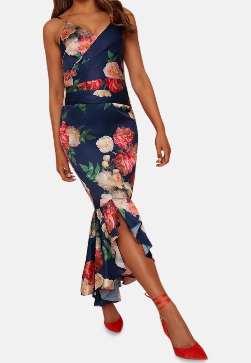 Robe fleurie bleu marine avec un modèle portefeuille, des bretelles fines et un ourlet évasé à volants. À assortir avec des escarpins rouges pour un contraste.
