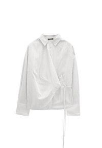 Koszula na guziki w białe i jasnoszare pionowe paski. Miękki materiał, luźny krój, z wiązaniem w talii i klasycznym kołnierzem.