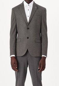 Grijze op maat gemaakte blazer met notched lapels, twee zwarte knopen en zijzakken, gecombineerd met een witte blouse met een kraag en blauwe knopen.
