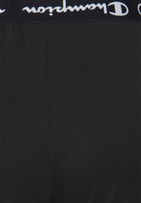 Schwarze Baumwoll-Boxershorts mit einem breiten elastischen Bund und weißem "Champion"-Logo. Glatte Textur und taillierte Passform.